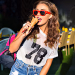 attractive-young-woman-stylish-wear-posing-looking-woman-eating-ice-cream-outdoors-sports-bag-her-shoulder-bright-clothes-sunglasses_291049-678