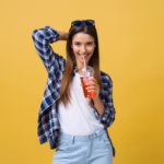 fashion-pretty-young-woman-with-fresh-fruit-juice-cup-blue-shirt-having-fun-colorful-yellow-background_1258-104677